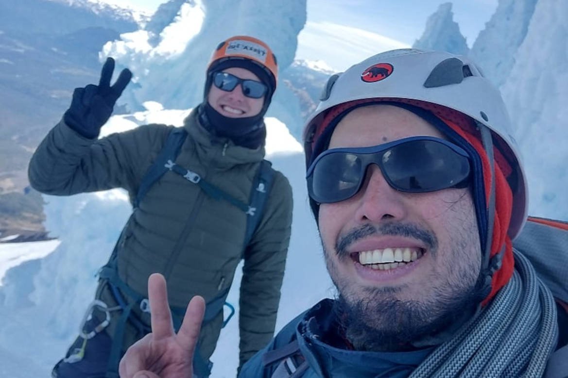 Dos personas con casco y lentes de sol sonríen entre formaciones de hielo