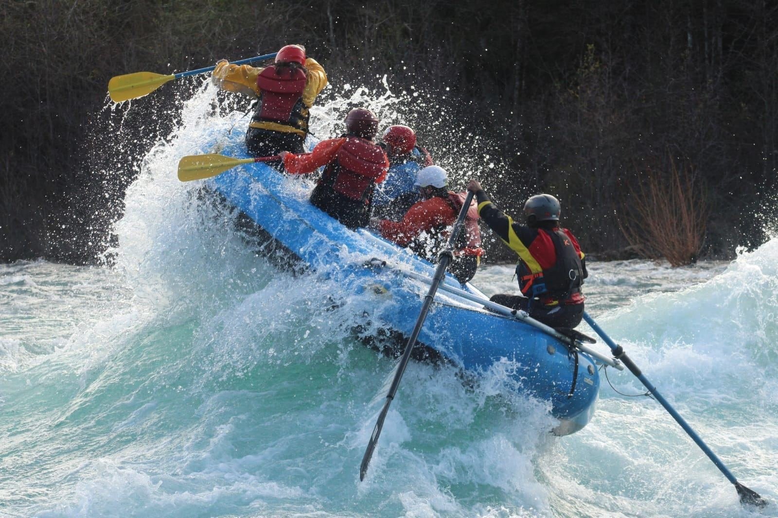 A blue raft climbs a big wave in a rapid on the Petrohue River