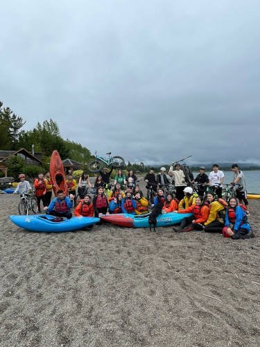 Group with kayaks and bikes posing on the beach in front of the base