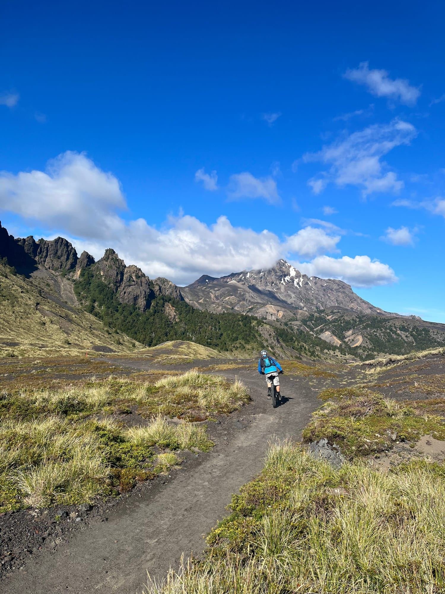 Ciclista baja por un sendero en un valle abierto, con cerros al fondo