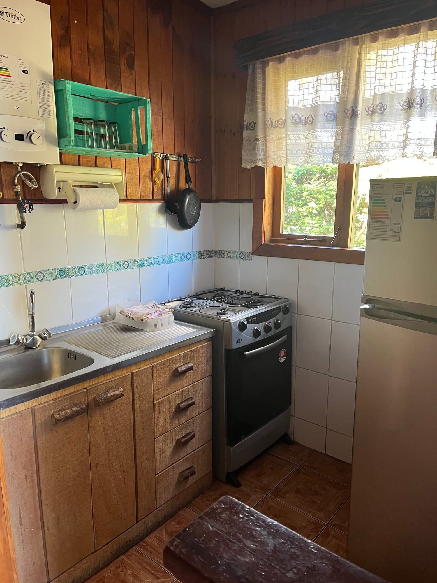 A cabin kitchen with a gas stove, a fridge and a sink
