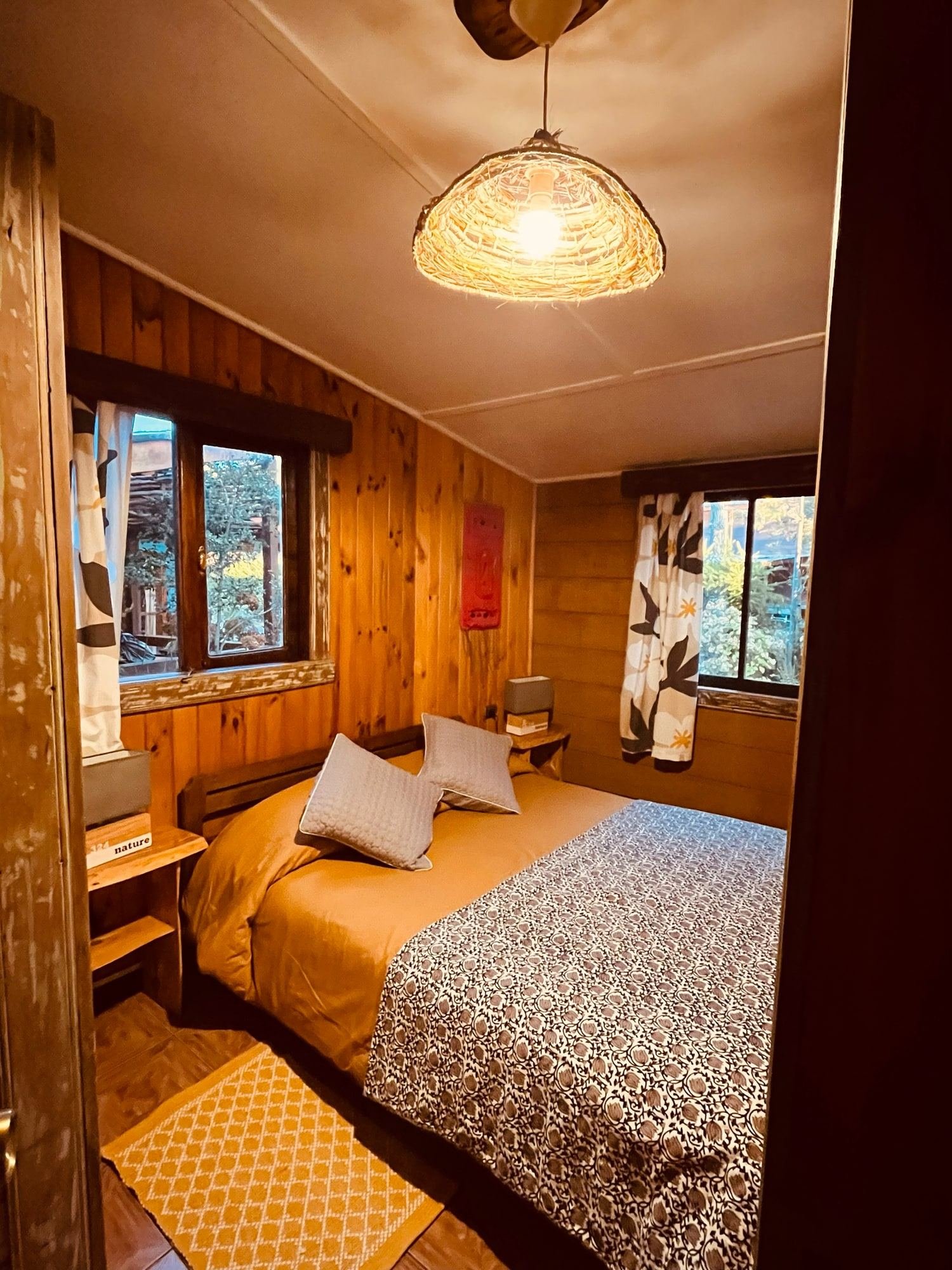A cabin bedroom with a double bed and two windows