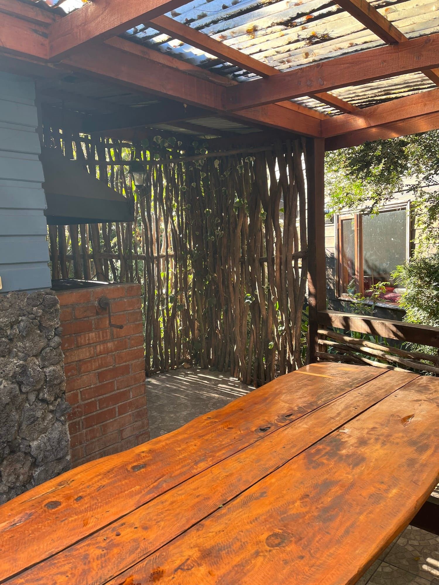 A cabin's covered terrace with a wooden table and a grill
