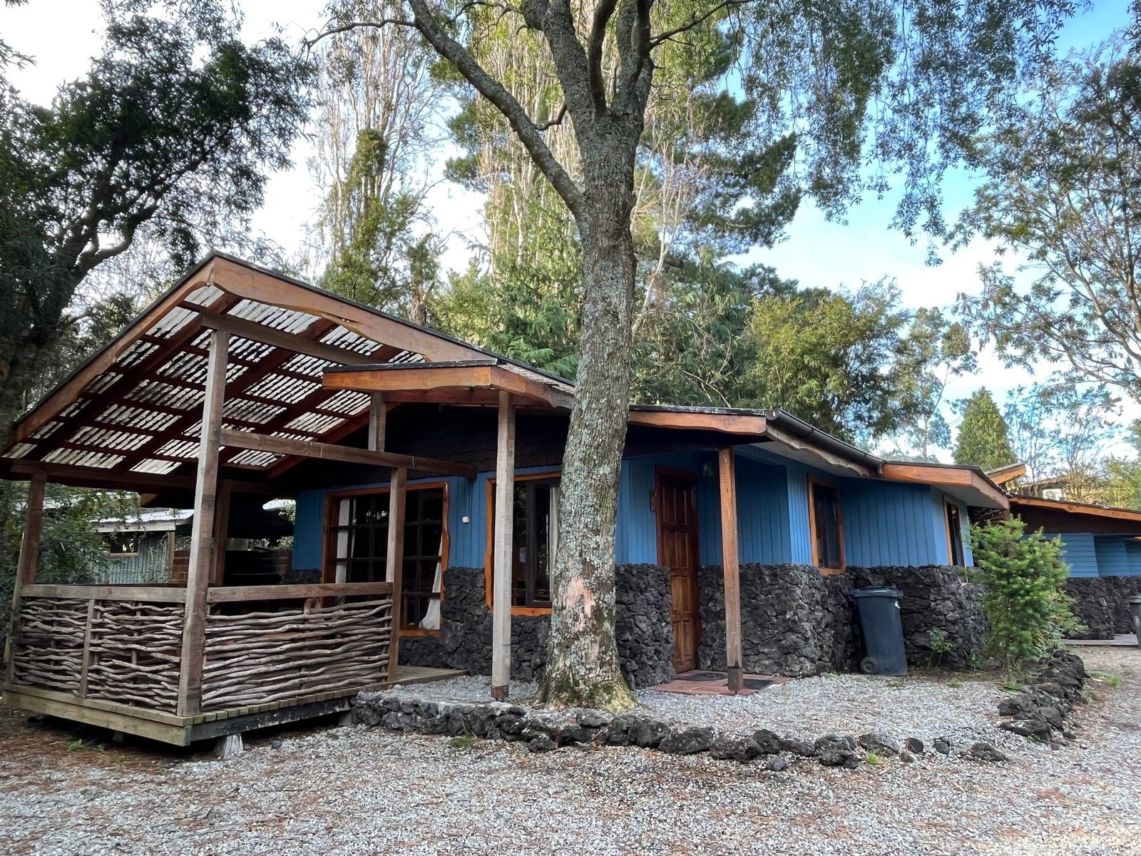 Blue wooden cabins with a covered terrace among the trees