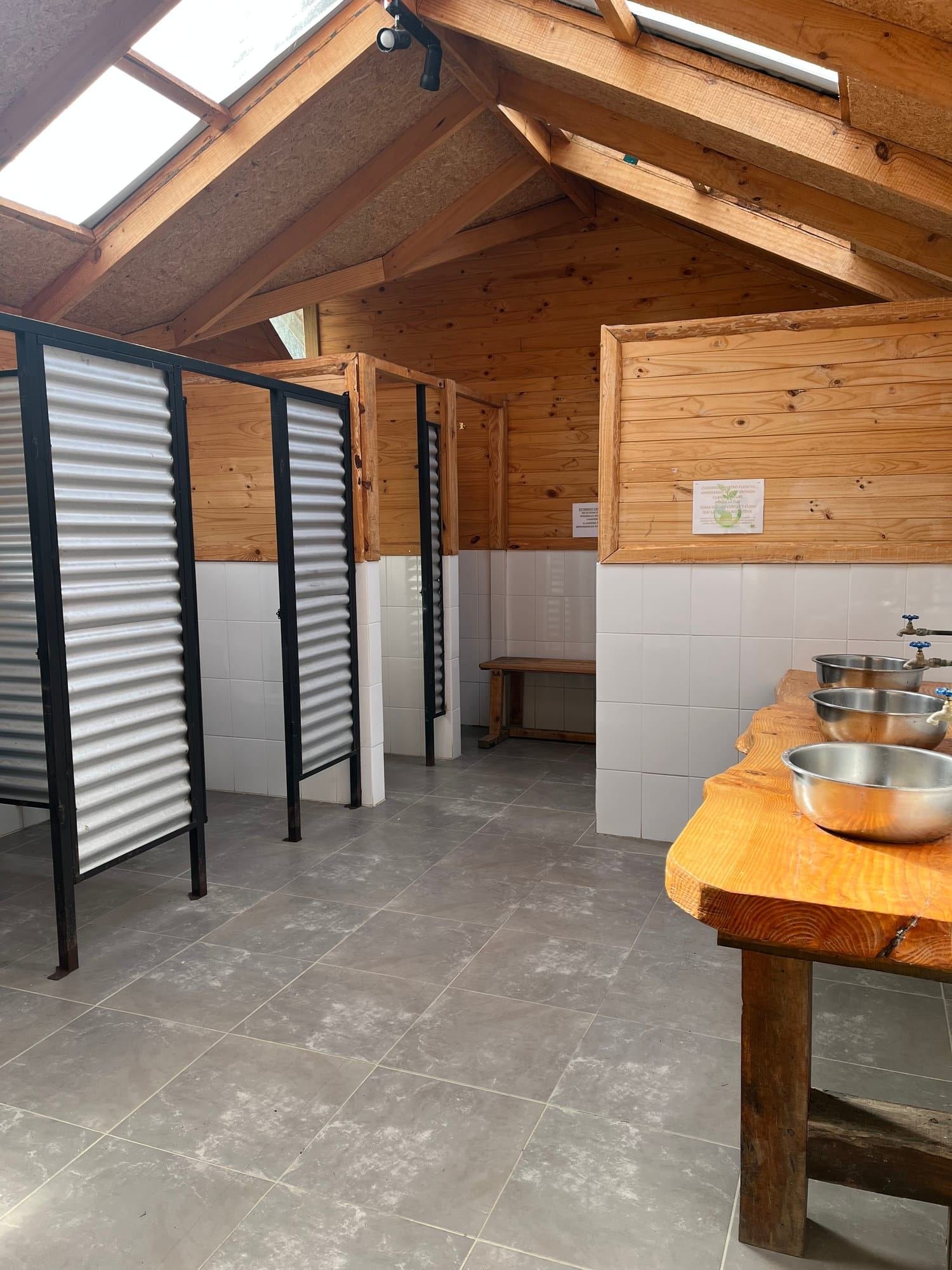 Interior de madera de los baños del camping, con mesón y lavaplatos