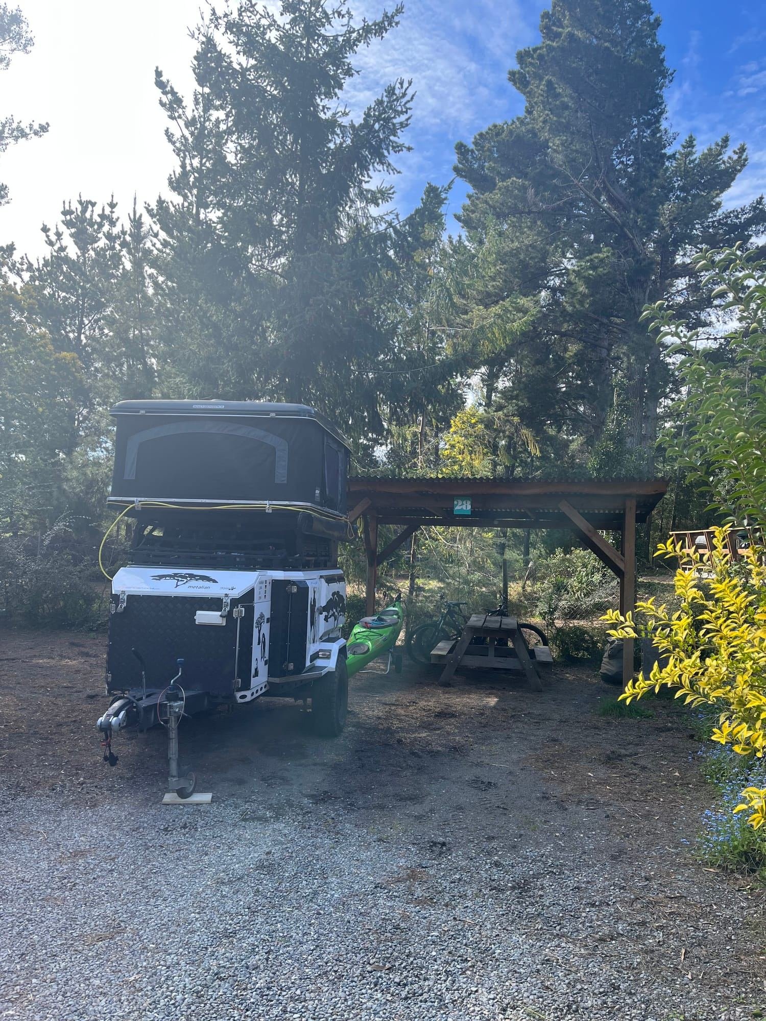 Vehículo de viaje estacionado junto a un sitio techado del camping