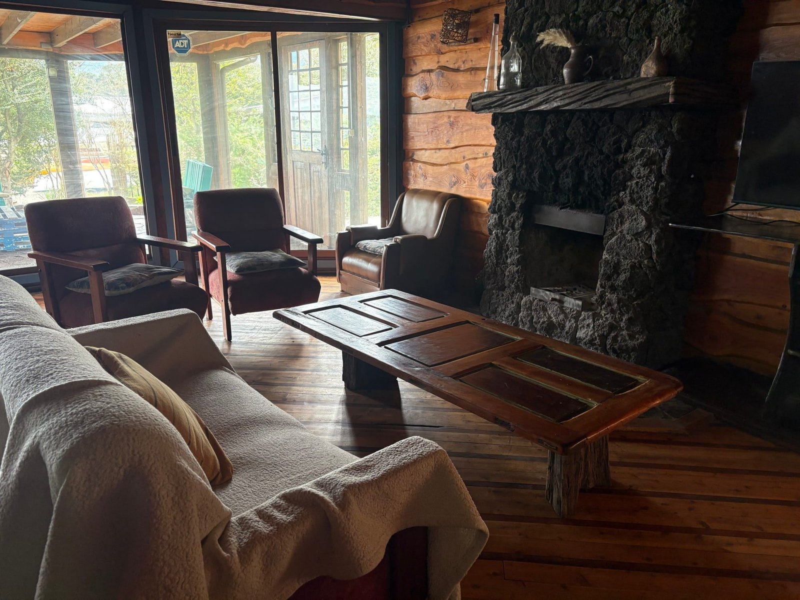 The beach house living room with armchairs and a stone fireplace