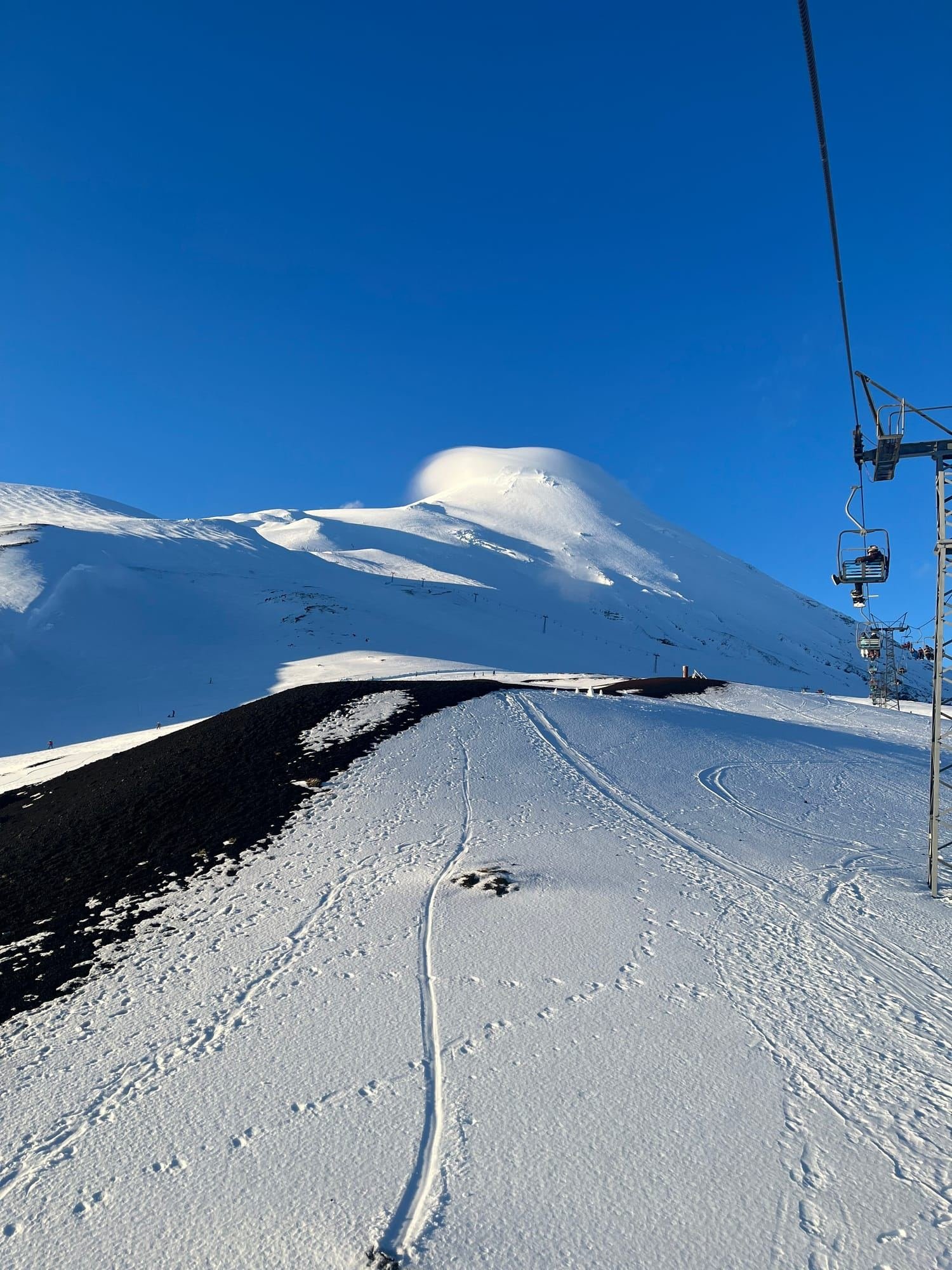A snowy run and the chairlift below the summit of Osorno Volcano