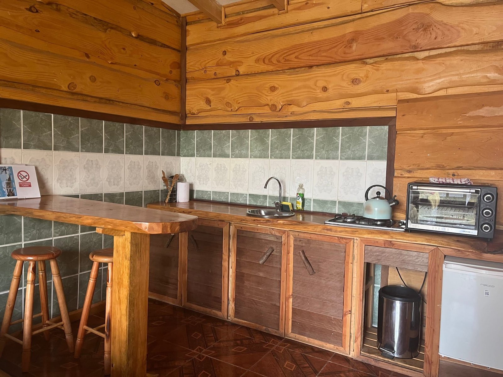 An apartment kitchen with a wooden bar and two stools