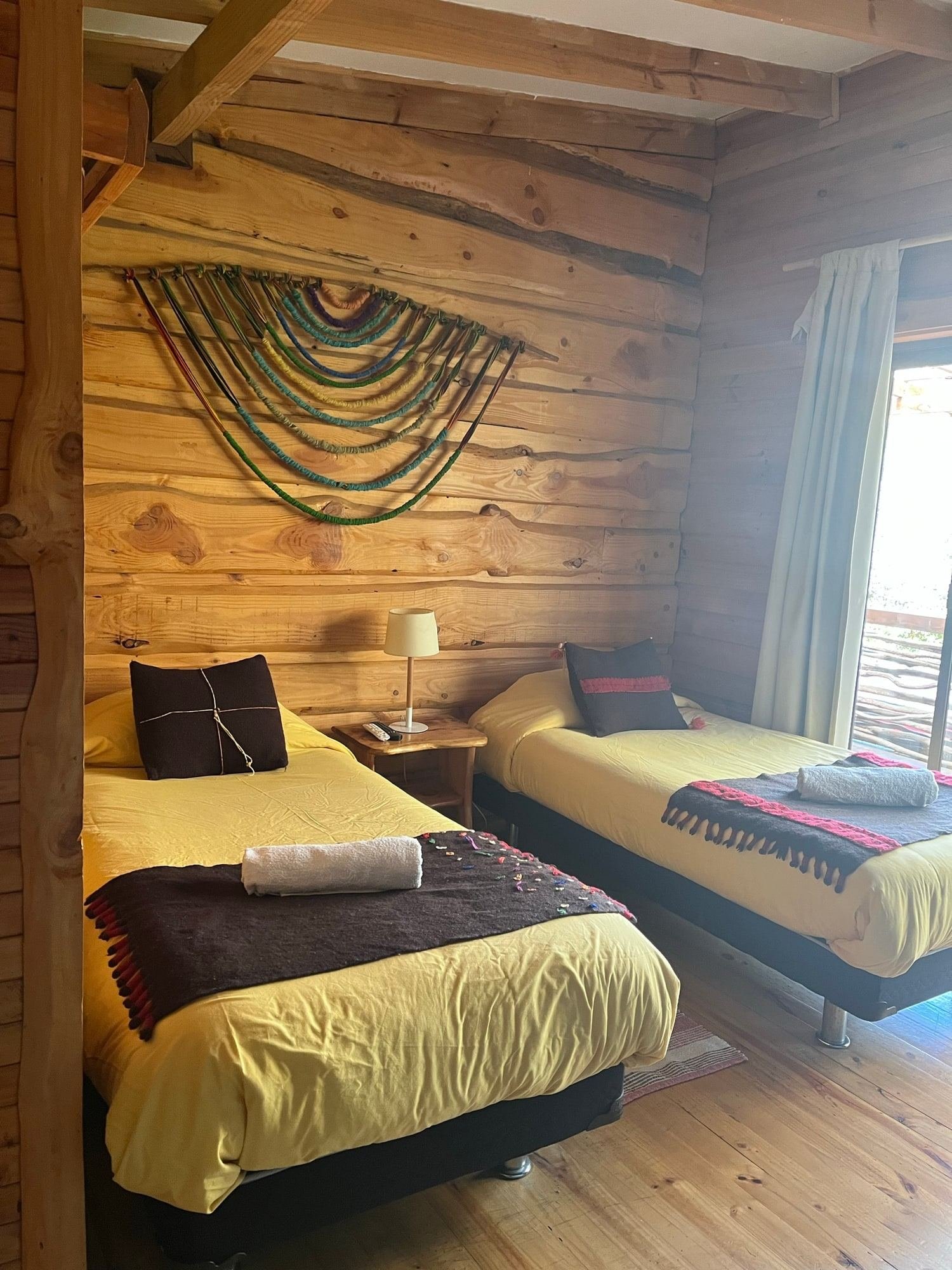 An apartment with two single beds and a wooden wall