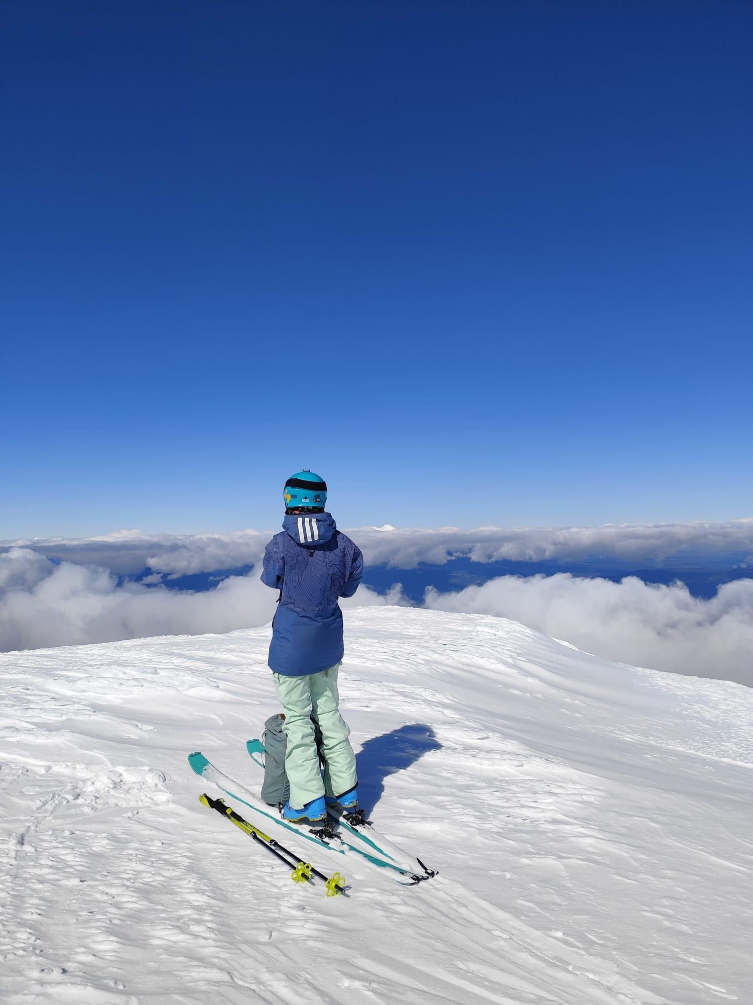 A skier looks over a sea of clouds from the snow of Osorno Volcano