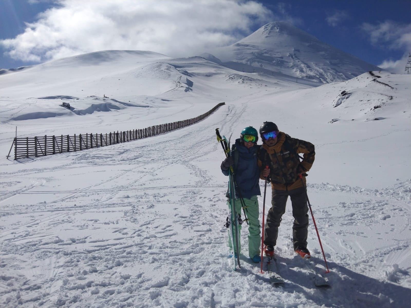 Two skiers at the ski resort, with the summit of Osorno Volcano behind