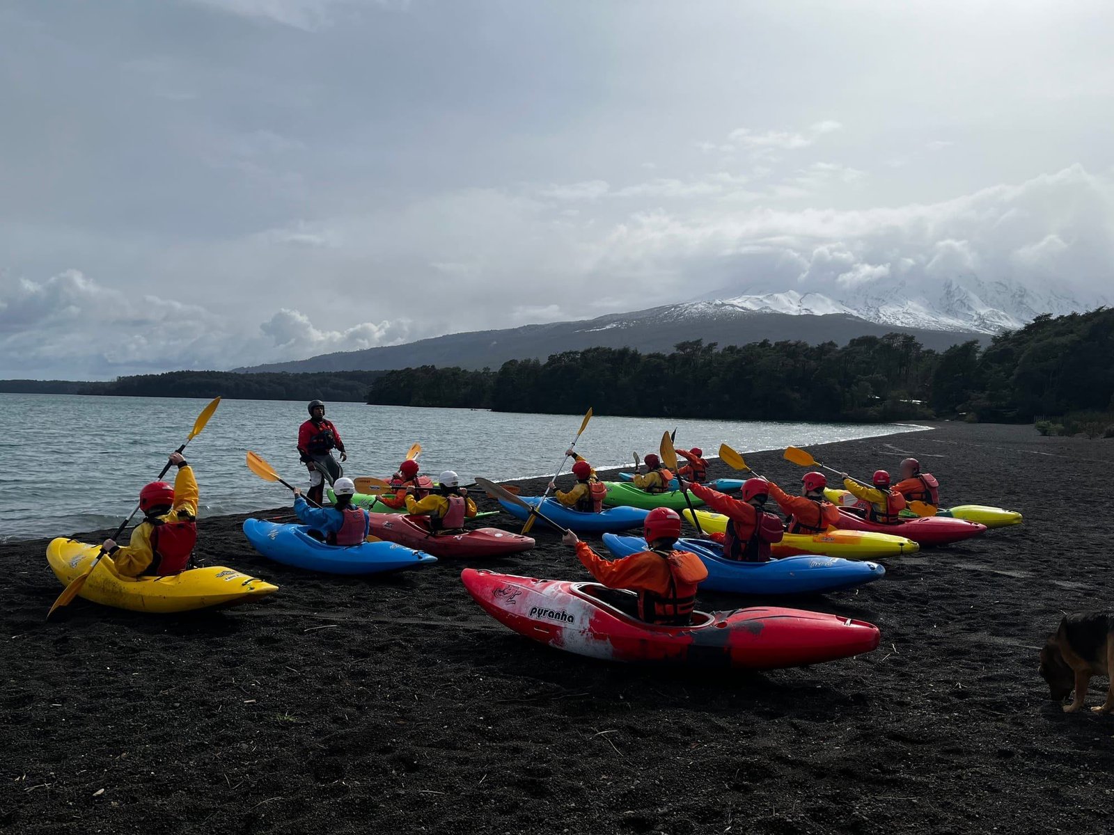 A group in colorful kayaks on the Lake Llanquihue beach, with the volcano behind