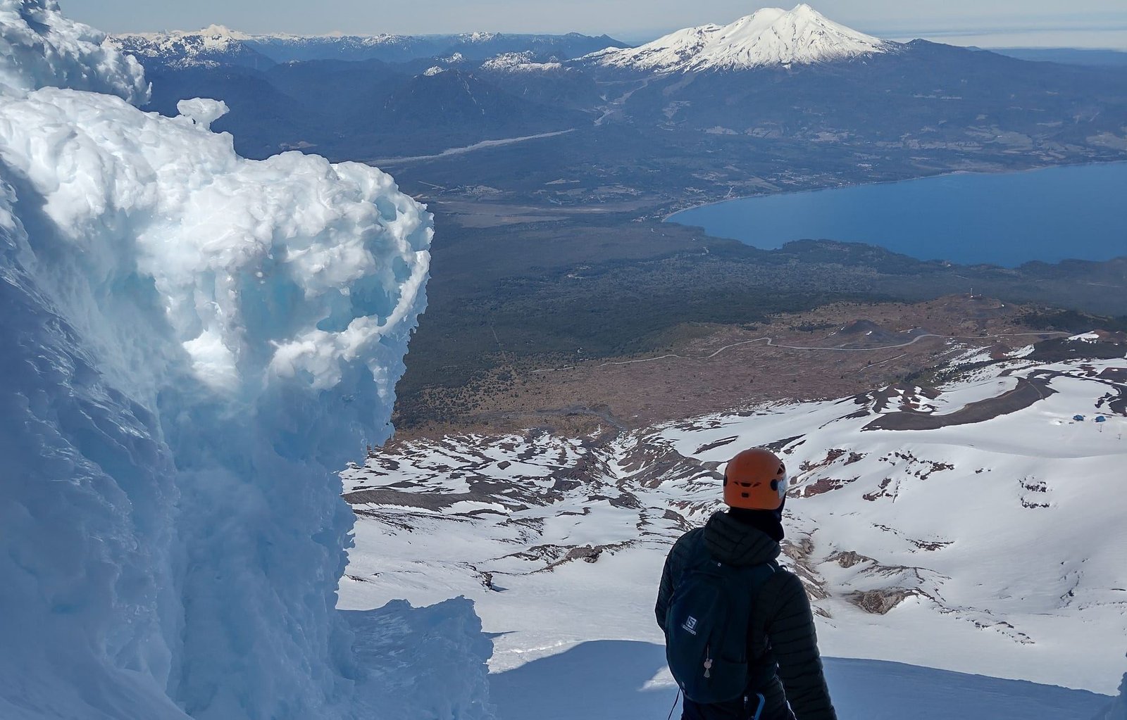 A climber in a helmet beside ice formations on the Osorno Volcano glacier