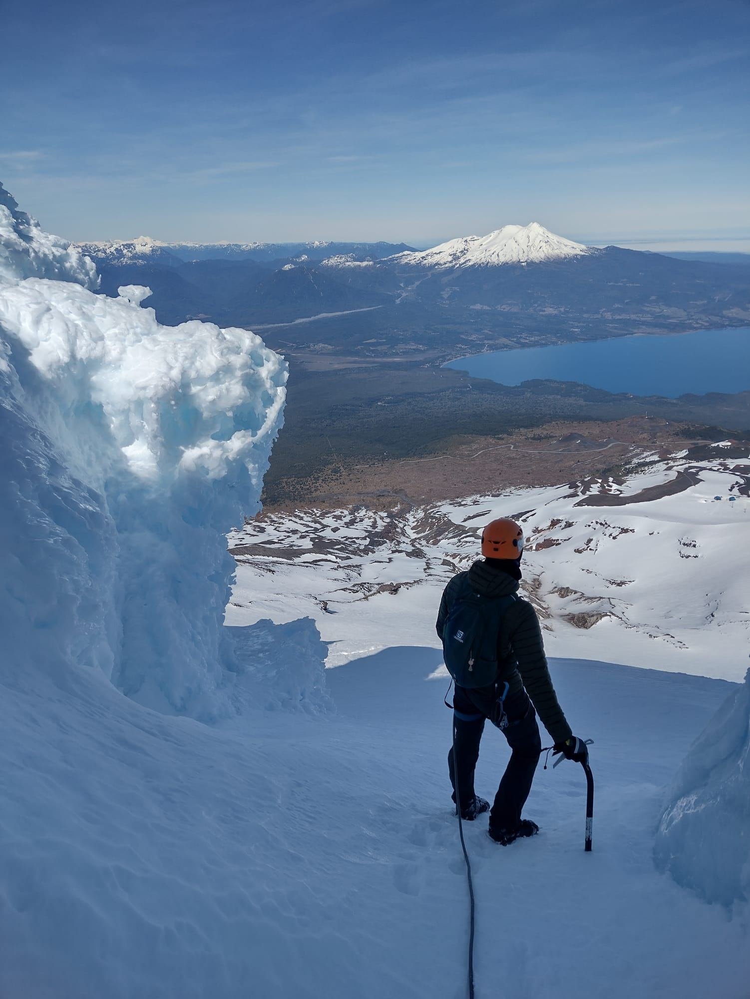 Montañista con casco junto a formaciones de hielo en el glaciar del Volcán Osorno