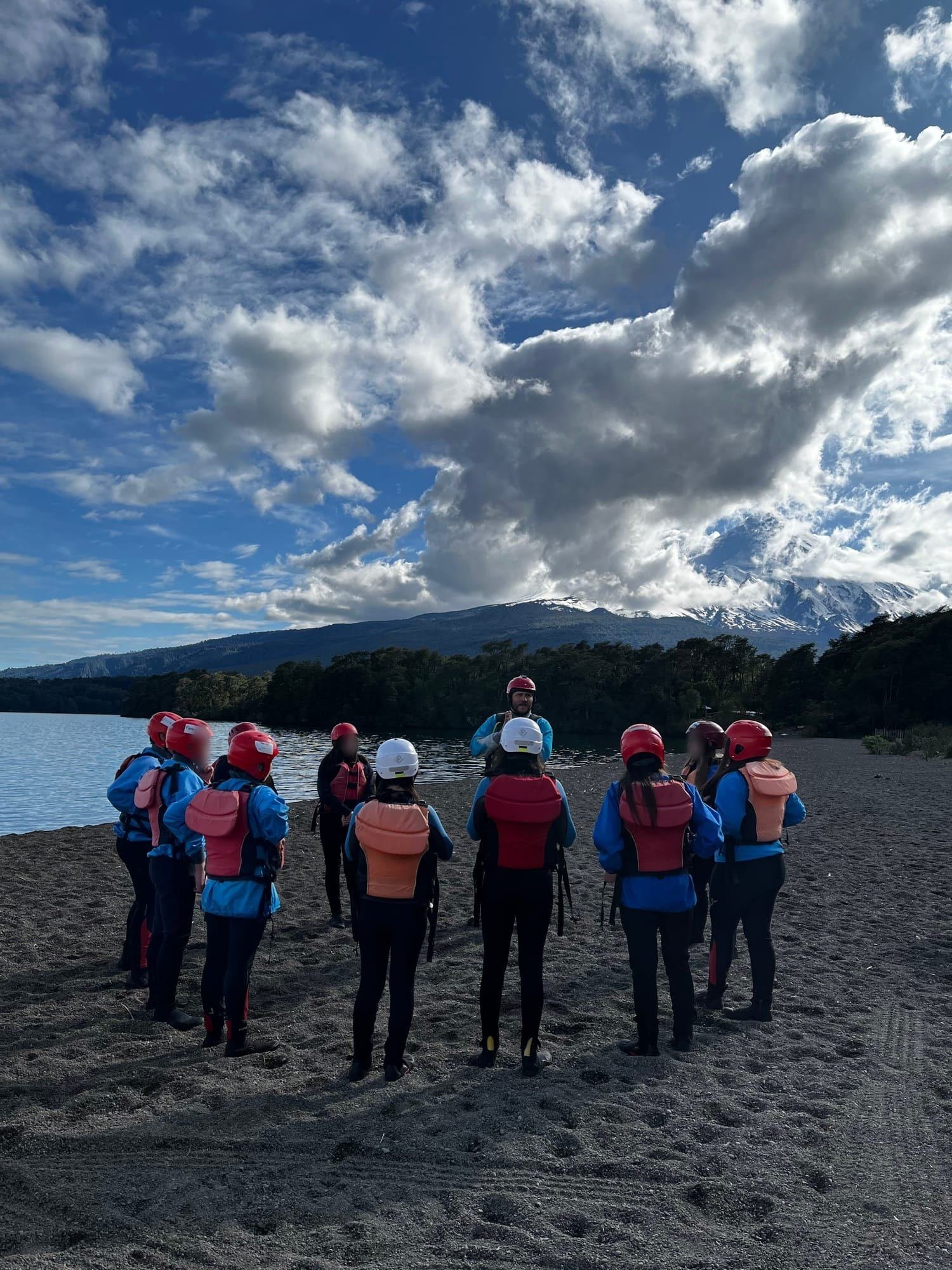 A group in life jackets listens to the guide's briefing on the beach
