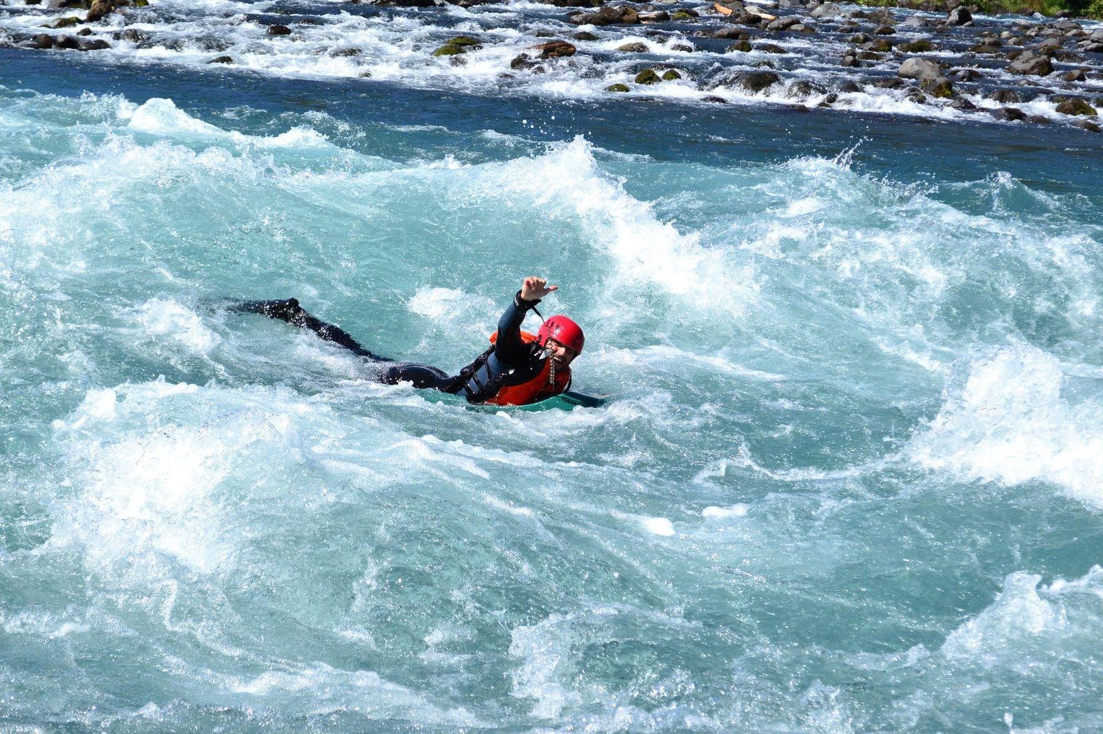 A person rides a white water rapid on a hydrospeed board
