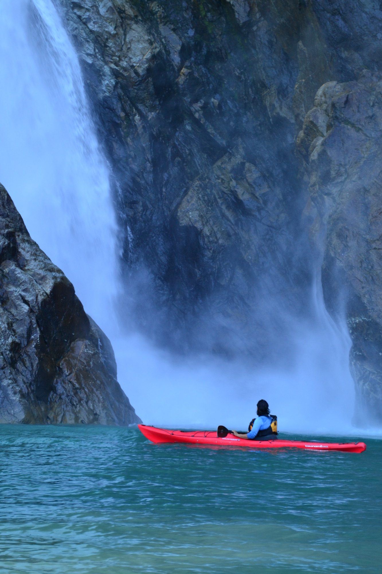 A red kayak below a tall waterfall on Lake Tagua Tagua