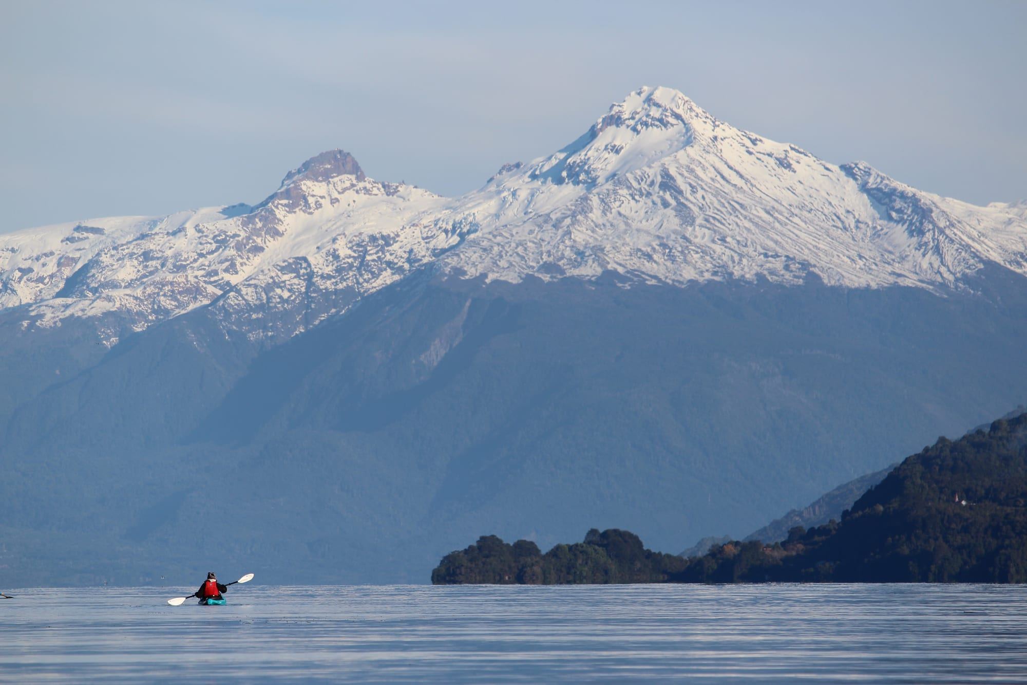A kayak on the Reloncaví Estuary facing snow-capped Yate Volcano, on the road to the hot springs
