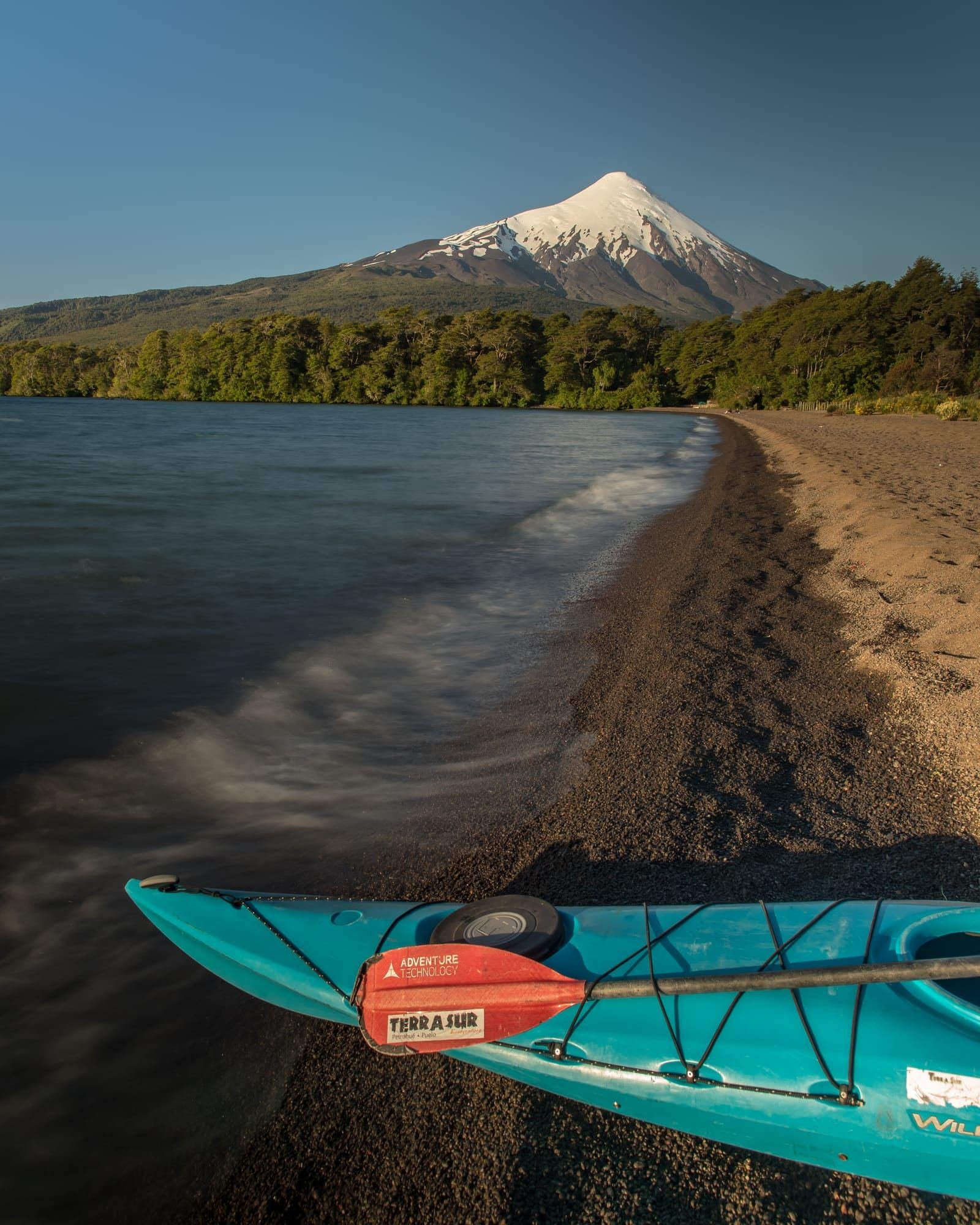 Kayak turquesa en la playa del Lago Llanquihue, con el volcán Osorno al fondo