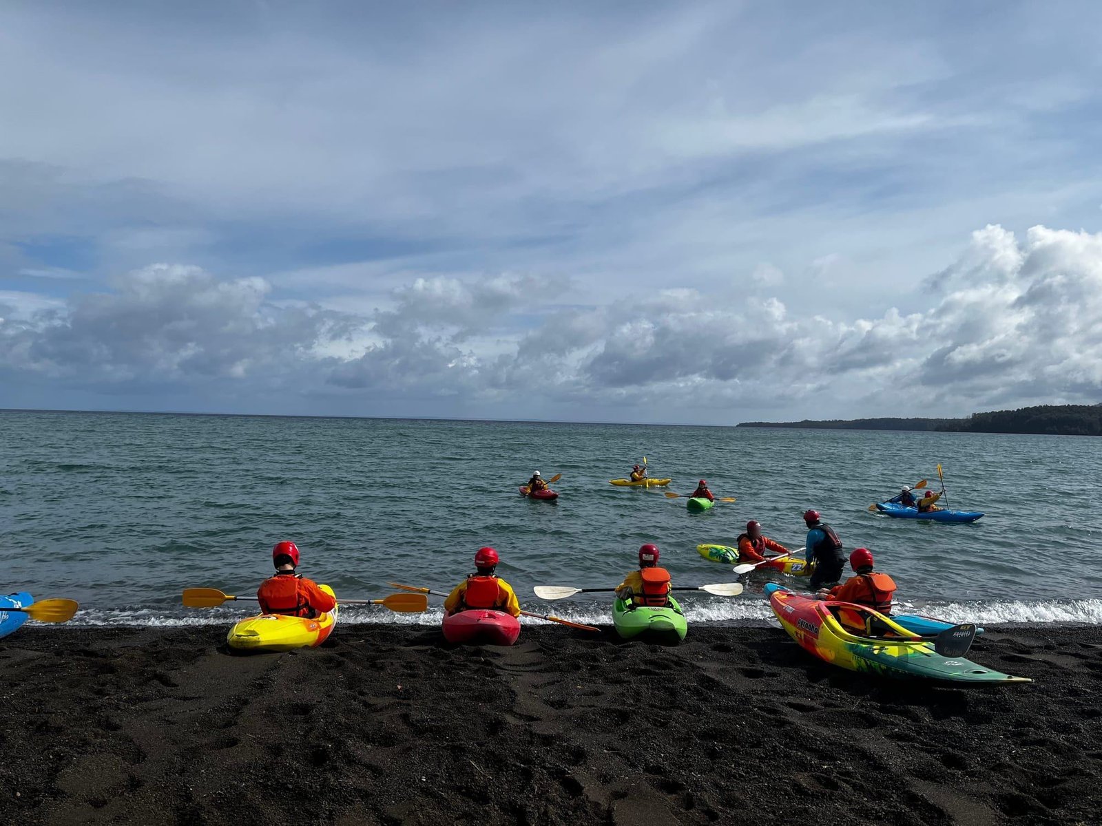 Students sitting in river kayaks on the beach before getting on the lake
