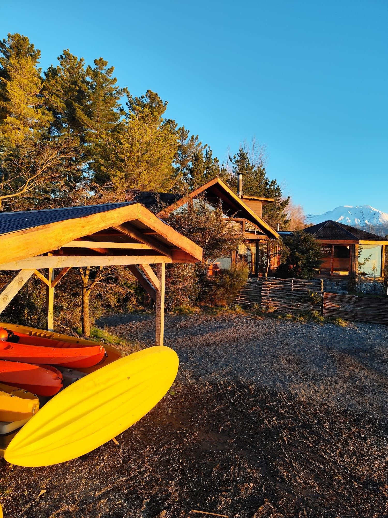 Tablas de SUP y kayaks en la playa, junto a las cabañas, al atardecer