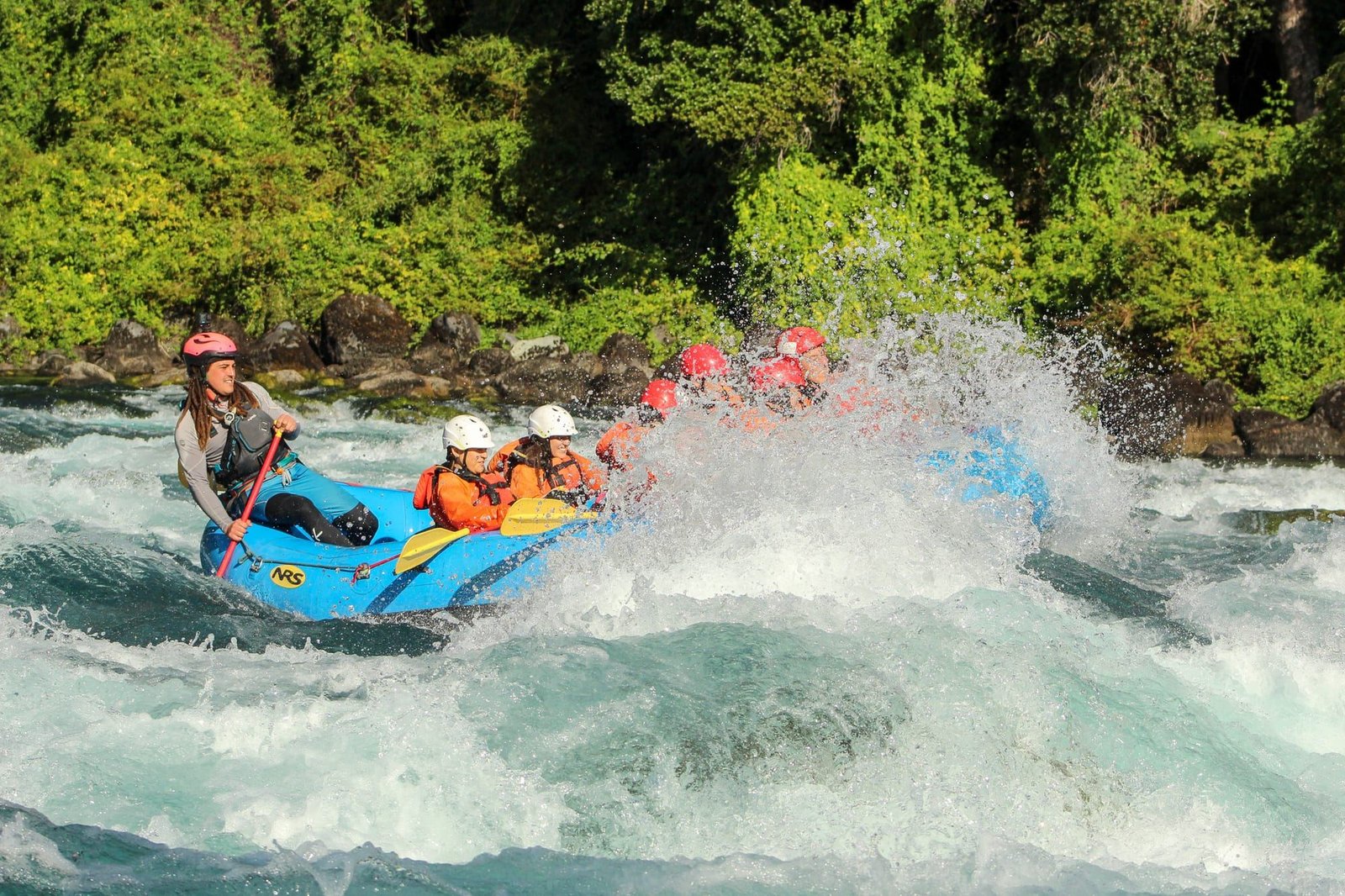 A raft with its guide enters a rapid on the Petrohue River, with native forest on the bank