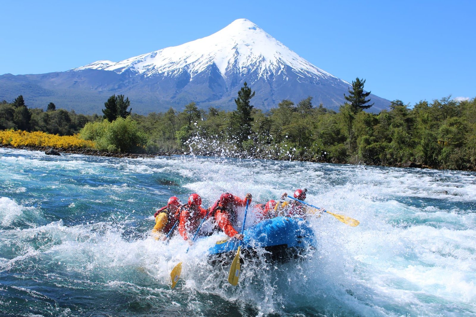 Balsa de rafting cruza un rápido del Río Petrohue con el volcán Osorno nevado de fondo