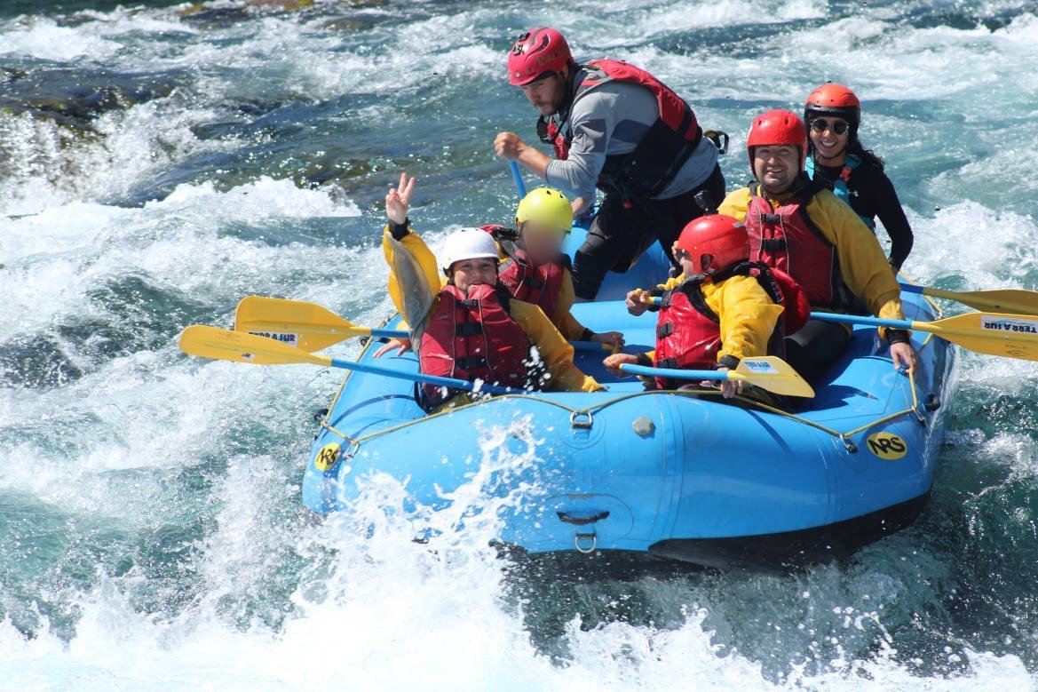 Group in helmets and life jackets running a class III rapid