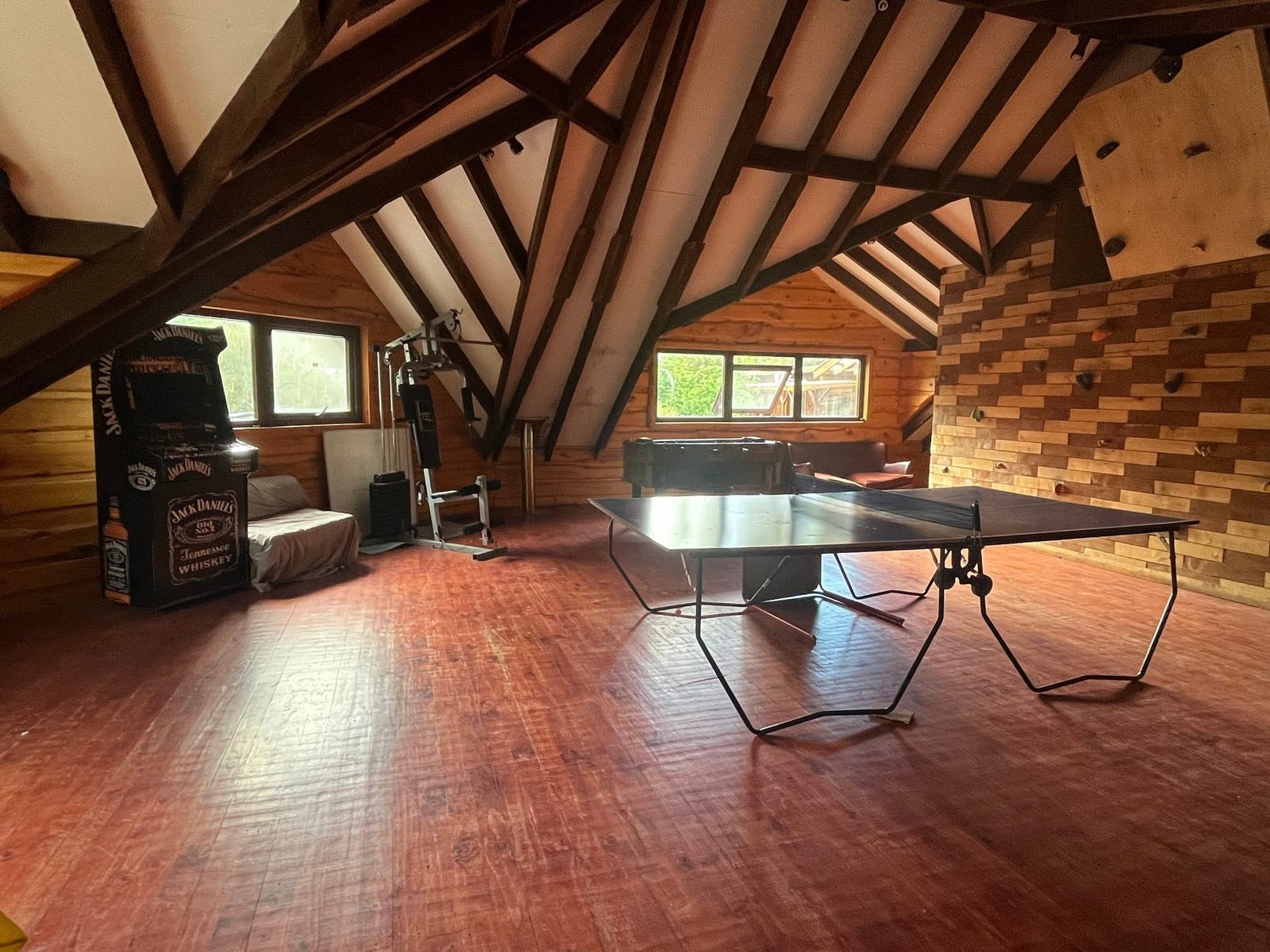 Segundo piso del salón, con mesa de ping-pong y techo de vigas a la vista