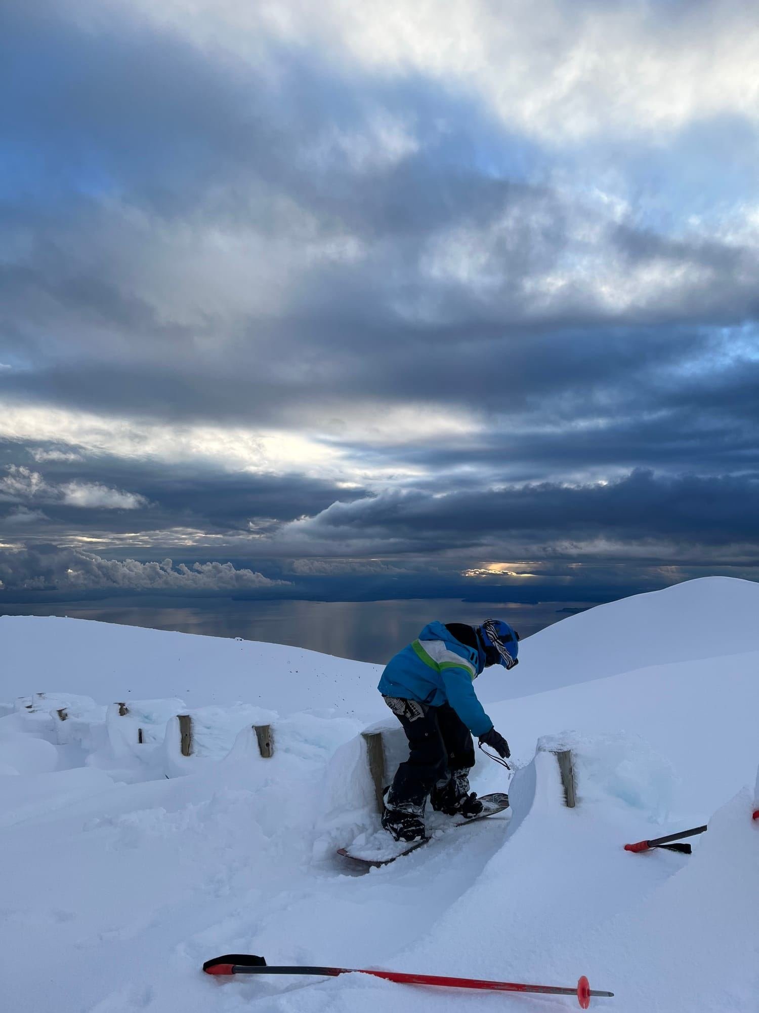 A snowboarder rides down the snow, with Lake Llanquihue behind