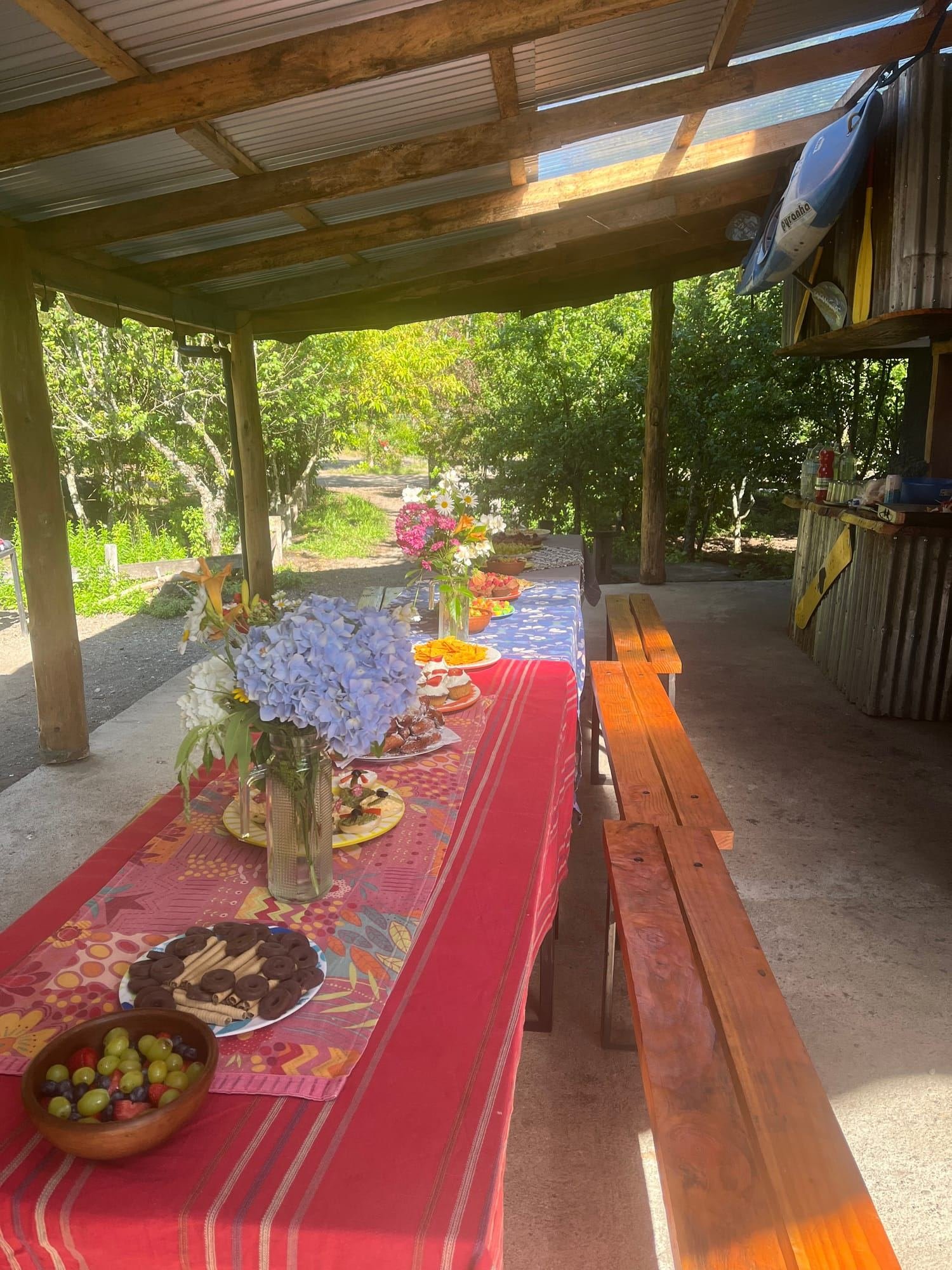 A long table with a red cloth and flowers on the covered terrace