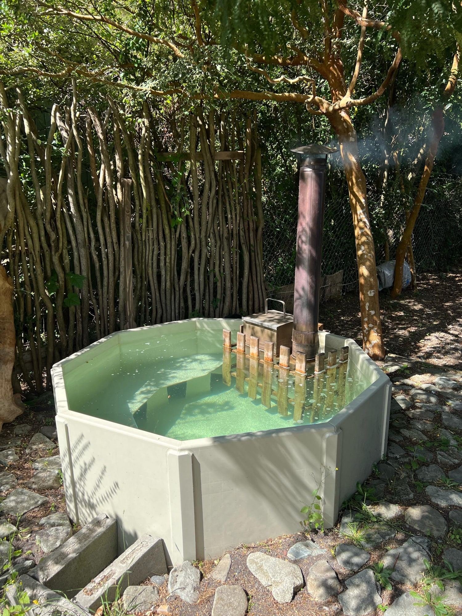 A wood-fired hot tub among the trees, next to the cabins