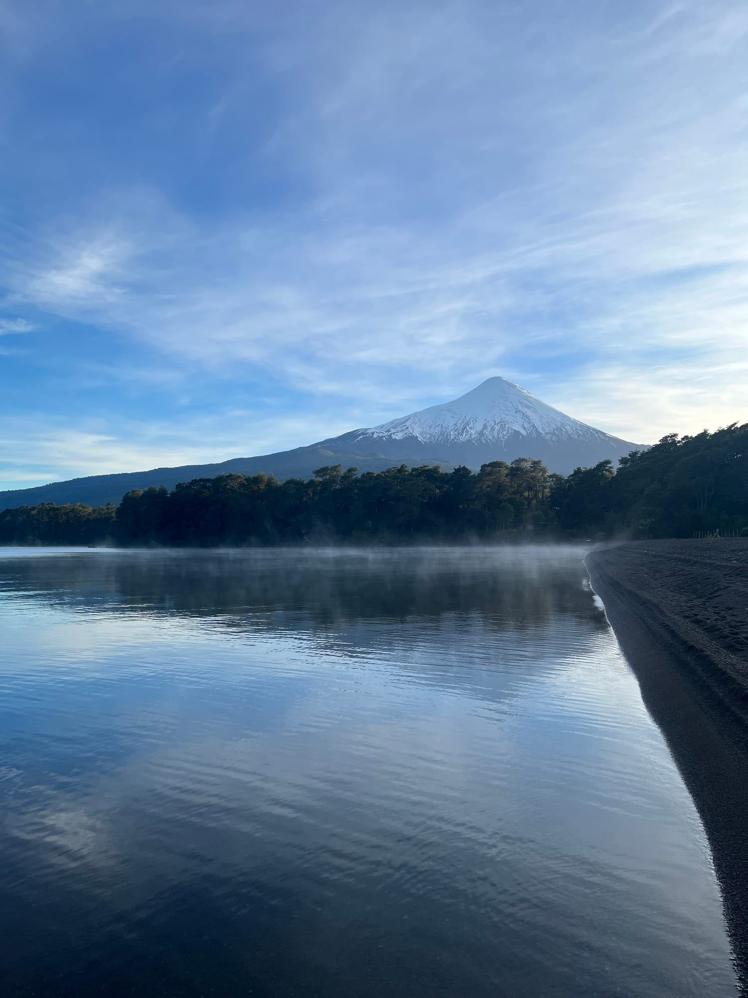 Volcán Osorno nevado sobre el bosque nativo y la orilla del Lago Llanquihue