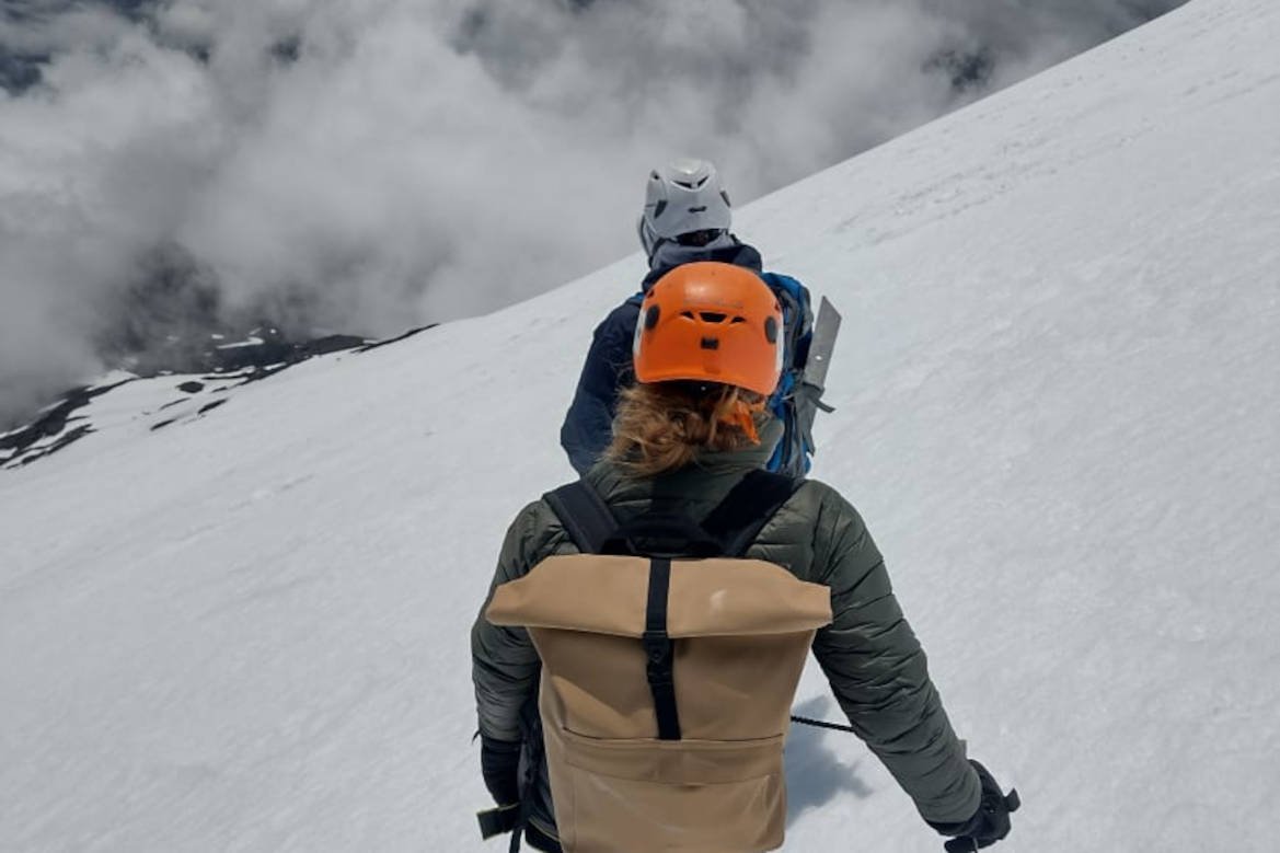 Two climbers in helmets crossing the snow among clouds